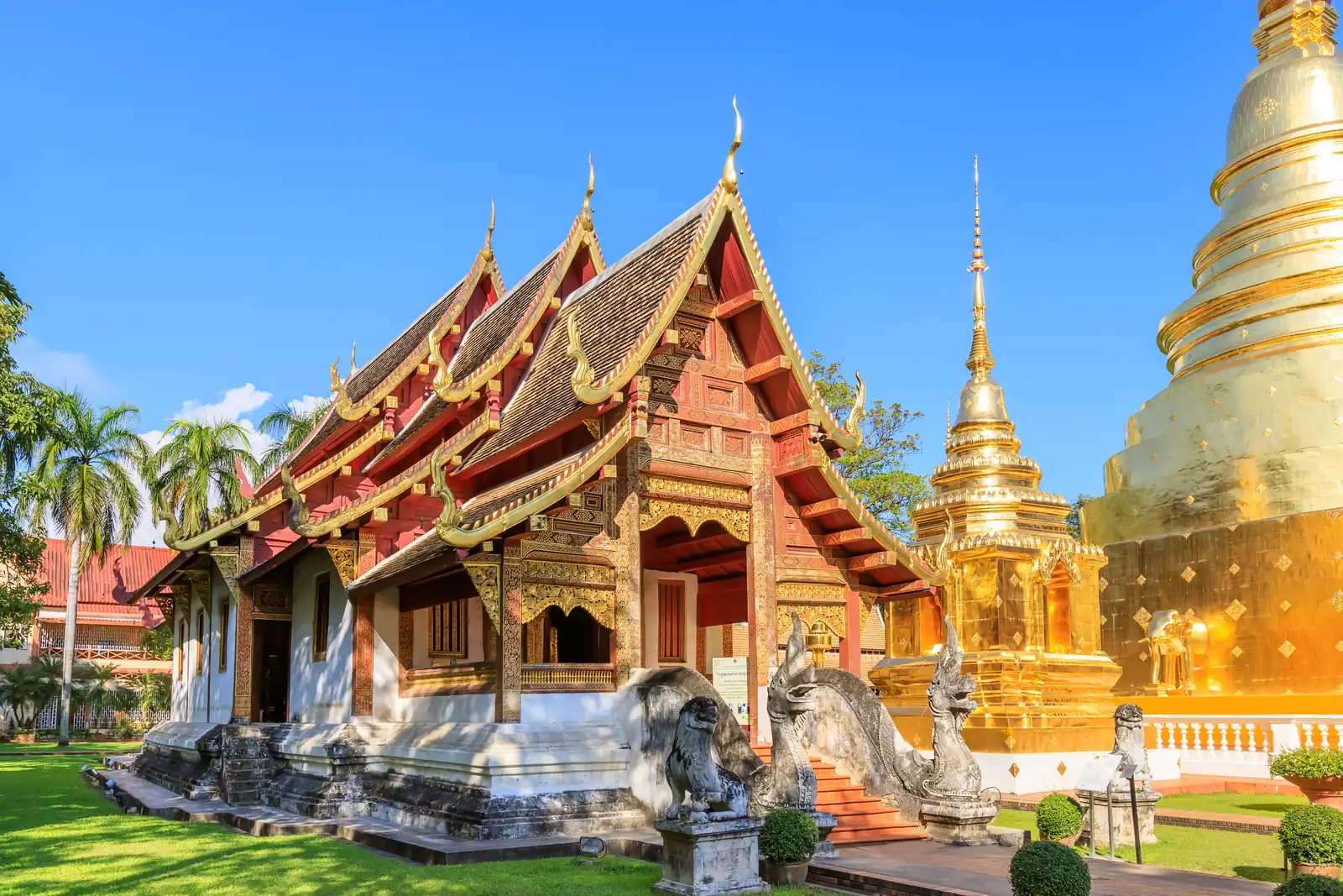 Carved Lanna-style chapel and golden chedi at Wat Phra Singh in Chiang Mai